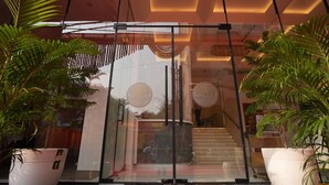 A modern building entrance with glass doors, a staircase, and potted plants. - Hotel Vedic Roots (Varanasi)