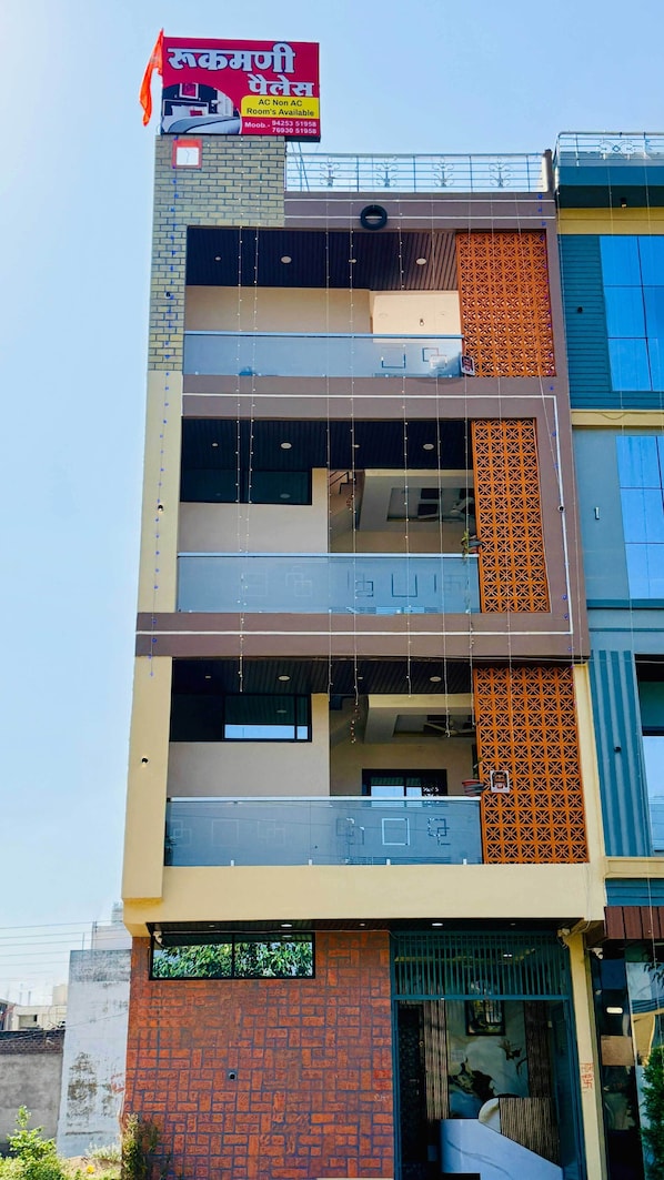 A multi-story building with a signboard advertising AC non-AC rooms.