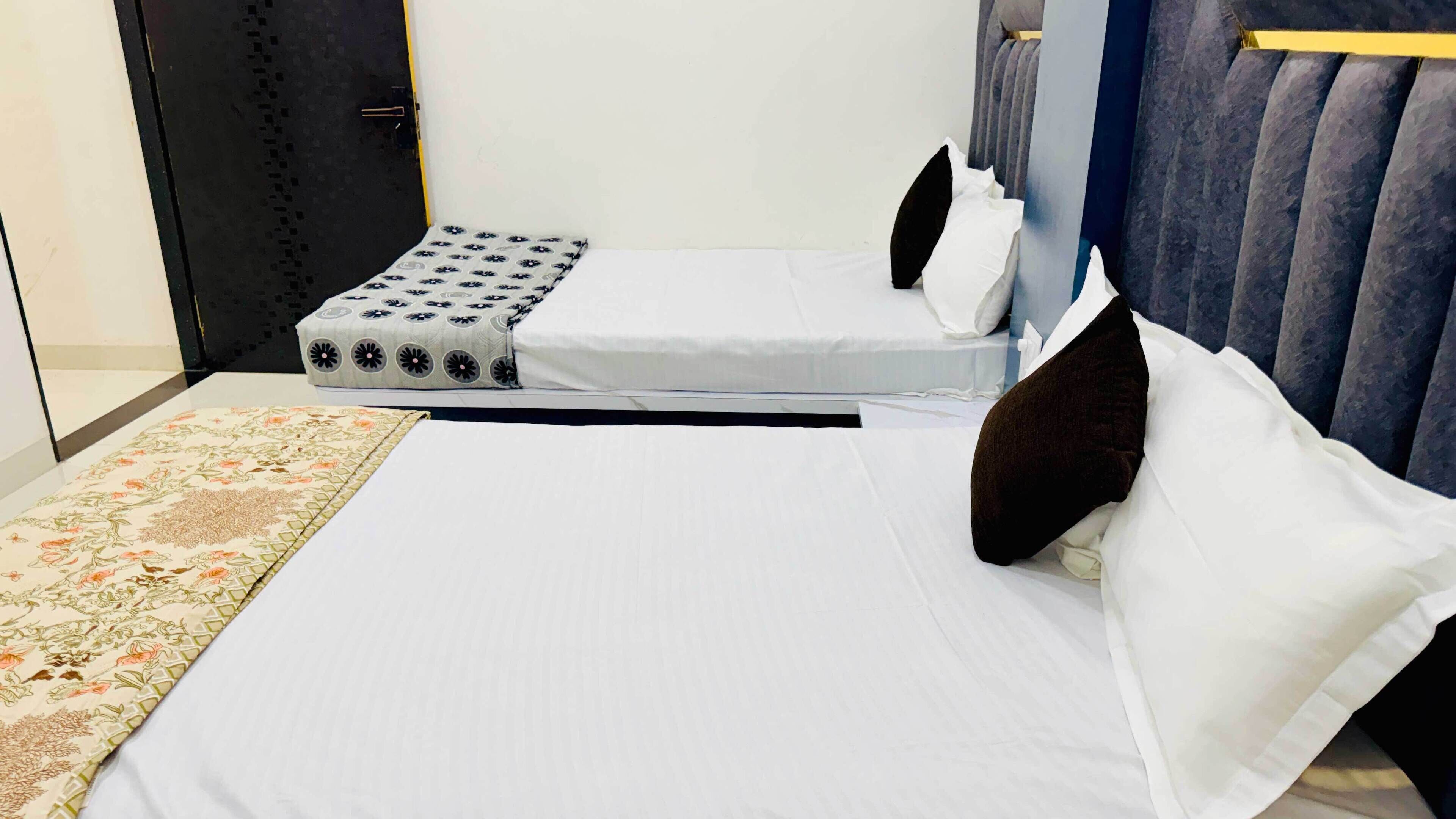 A neatly made bed with white linens, a patterned throw, and a bedside table with a lamp.