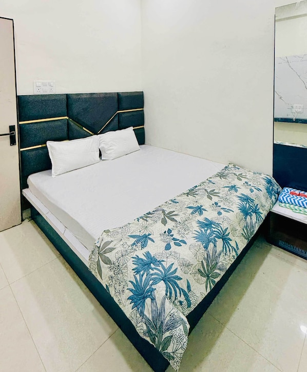 Un lit avec un matelas blanc et une couvre-lit à motifs floraux.