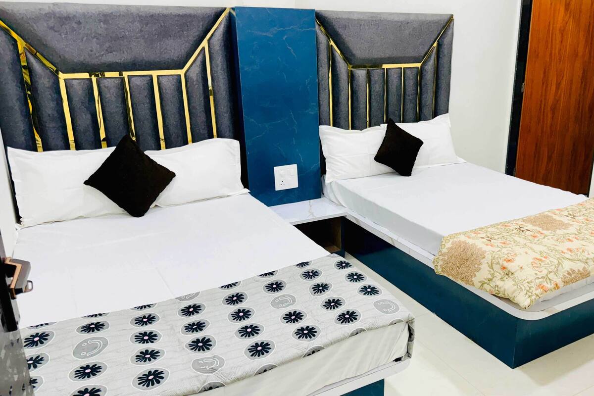 Ein Hotelzimmer mit zwei Betten, einer blauen Akzentwand und einer blumigen Bettdecke.