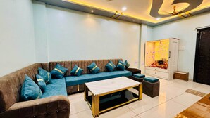 A modern living room with a brown sofa, blue cushions, a marble coffee table, and a decorative cabinet with a floral arrangement. - Rukmani Palace (Khandwa)