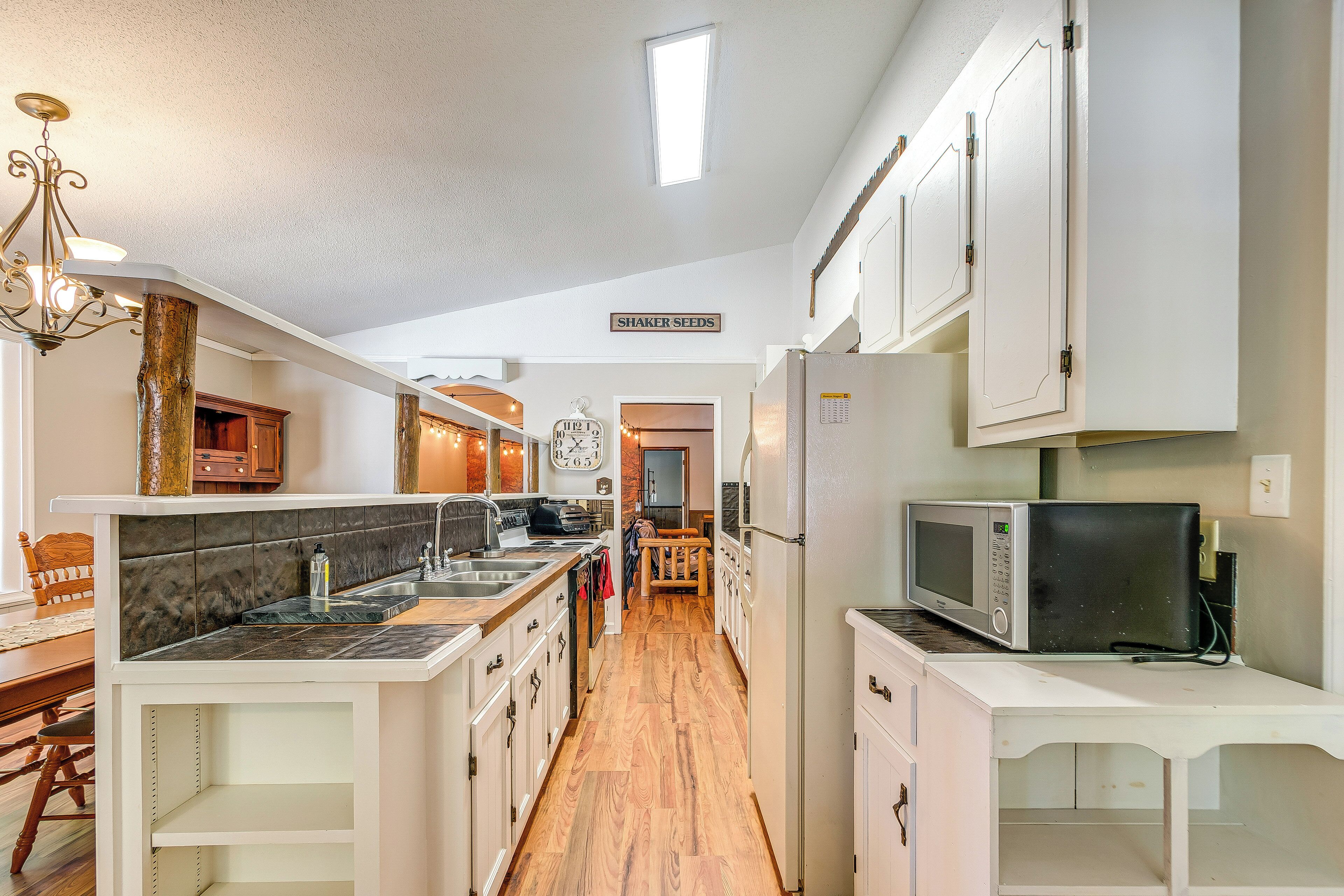 A modern kitchen with white cabinetry, a wooden floor, and a built-in microwave.