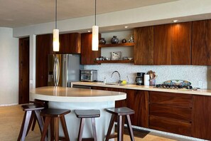 A modern kitchen with a central island, wooden cabinets, stainless steel appliances, and pendant lighting. - Dream Villa in Majahua (La Majahua)