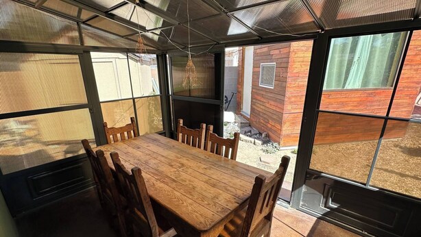 A wooden dining table with chairs in a sunlit room with large windows. - Albuquerque Gem Cozy, Central & Full of Charm (Albuquerque)