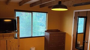 A bedroom with a bed, a dresser, a television on a shelf, and a window with blinds. - Albuquerque Gem Cozy, Central & Full of Charm (Albuquerque)