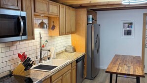 A modern kitchen with wooden cabinets, a stainless steel microwave, a built-in oven, a sink, and a wooden dining table. - Albuquerque Gem Cozy, Central & Full of Charm (Albuquerque)