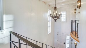 Un escalier avec une rampe en métal, un lustre et une porte en haut.
