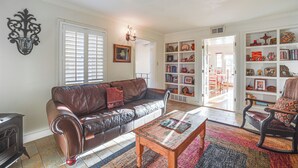 Un salon avec un canapé en cuir marron, une table basse en bois et une bibliothèque remplie d’objets décoratifs.