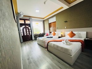 A hotel room with two beds, a sitting area, and a view of the outdoors. - Royal Hotel & Spa Hoi An (Da Nang)