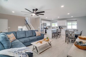 A modern living room with a blue sofa, a coffee table, and a dining area with a table and chairs. - 6 Mi to Saguaro Nat’l Park! Family Home w/ Patio (Tucson)