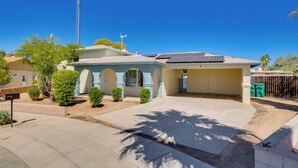 Una casa residencial con garaje, paneles solares y un cielo azul despejado.