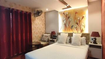 Una habitación de hotel con una cama grande, dos mesitas de noche, una pequeña mesa redonda y una obra de arte colgada en la pared.