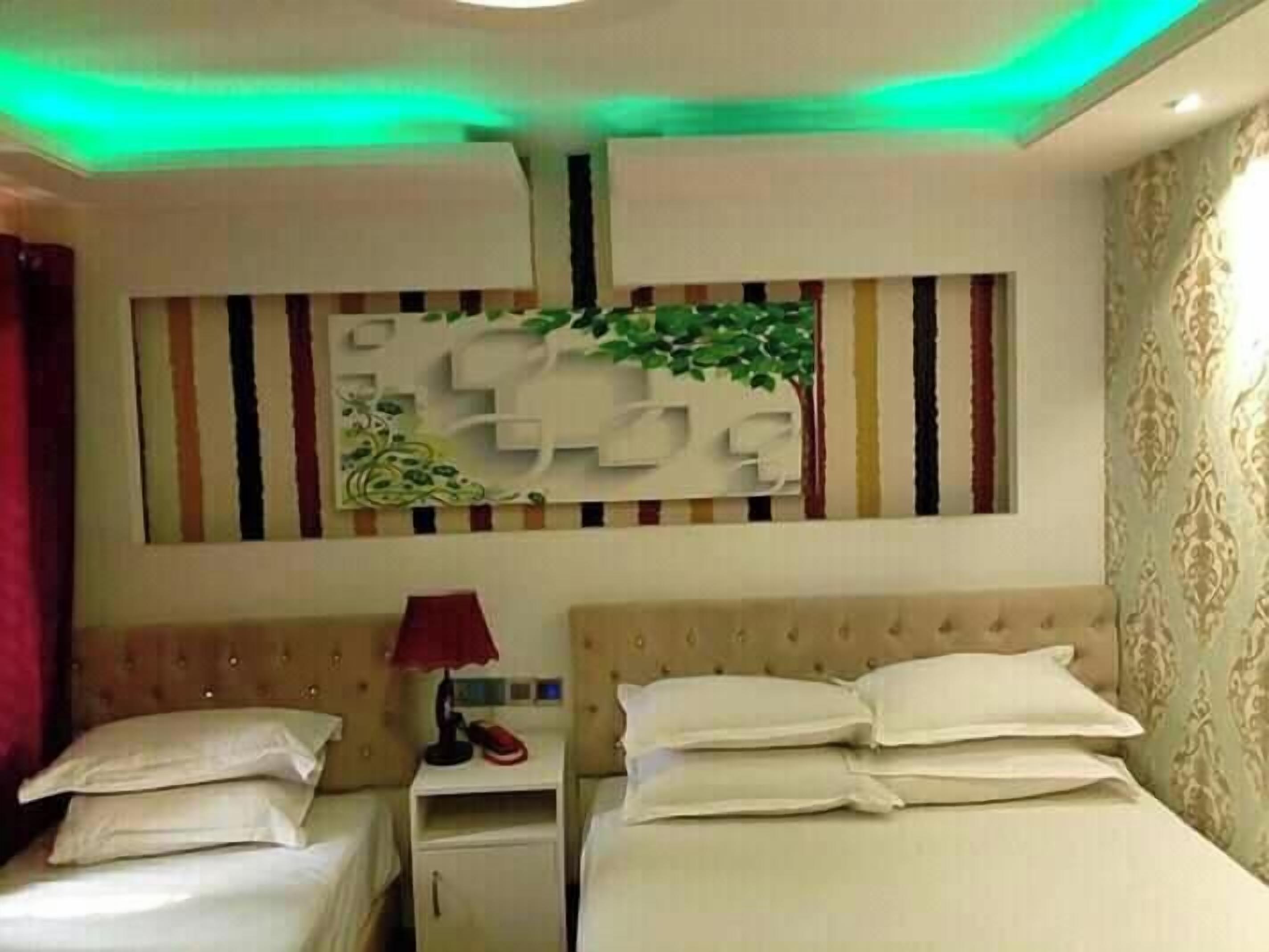 A hotel room with two beds, a nightstand, a lamp, and a decorative wall panel.