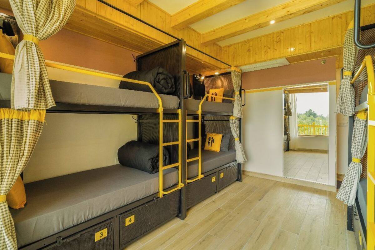 A bunk bed room with a wooden ceiling, a small table, and a window.