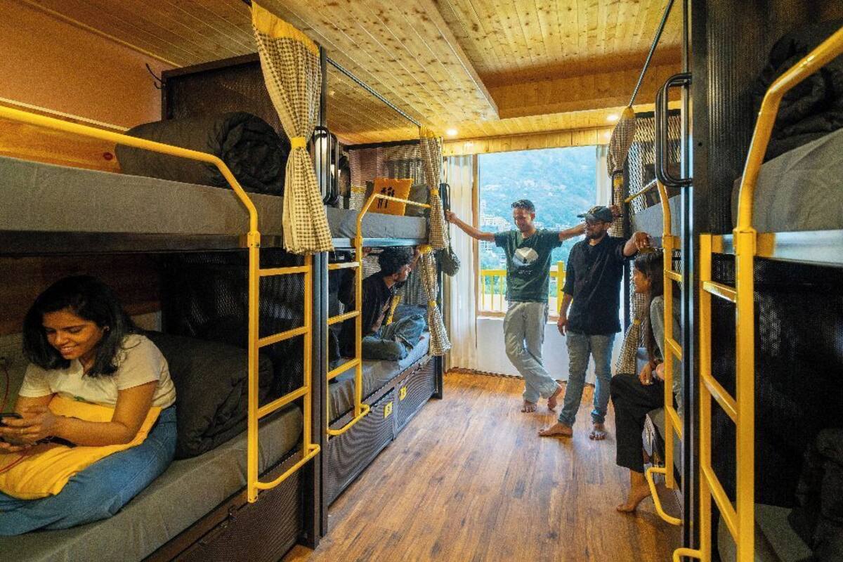 A train carriage with bunk beds, wooden flooring, and a view of the outside.