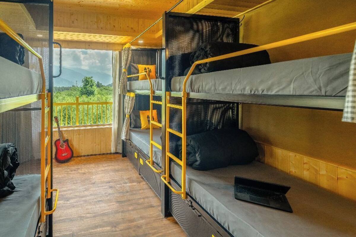 A bunk bed room with a view of greenery and mountains.