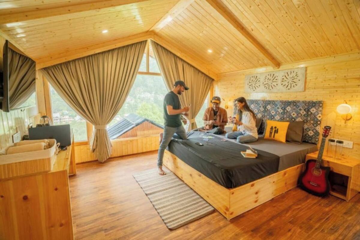A cozy bedroom with a wooden ceiling, a bed, a guitar, and a TV.