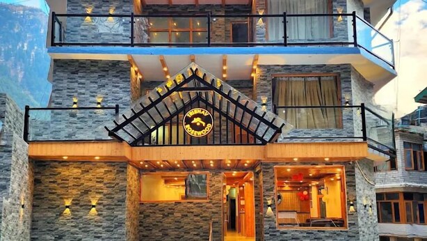 A multi-story building with a stone facade, a balcony with railings, and a sign indicating a hotel. - Rosewood Manali (Manali)