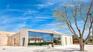 Een modern gebouw met grote glasramen, een gevel van natuursteen en een boom op de voorgrond.
