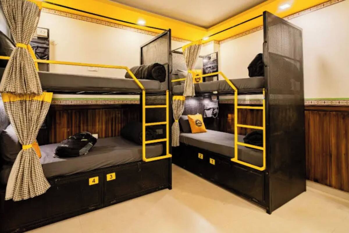A bunk bed room with yellow railings and checkered curtains.