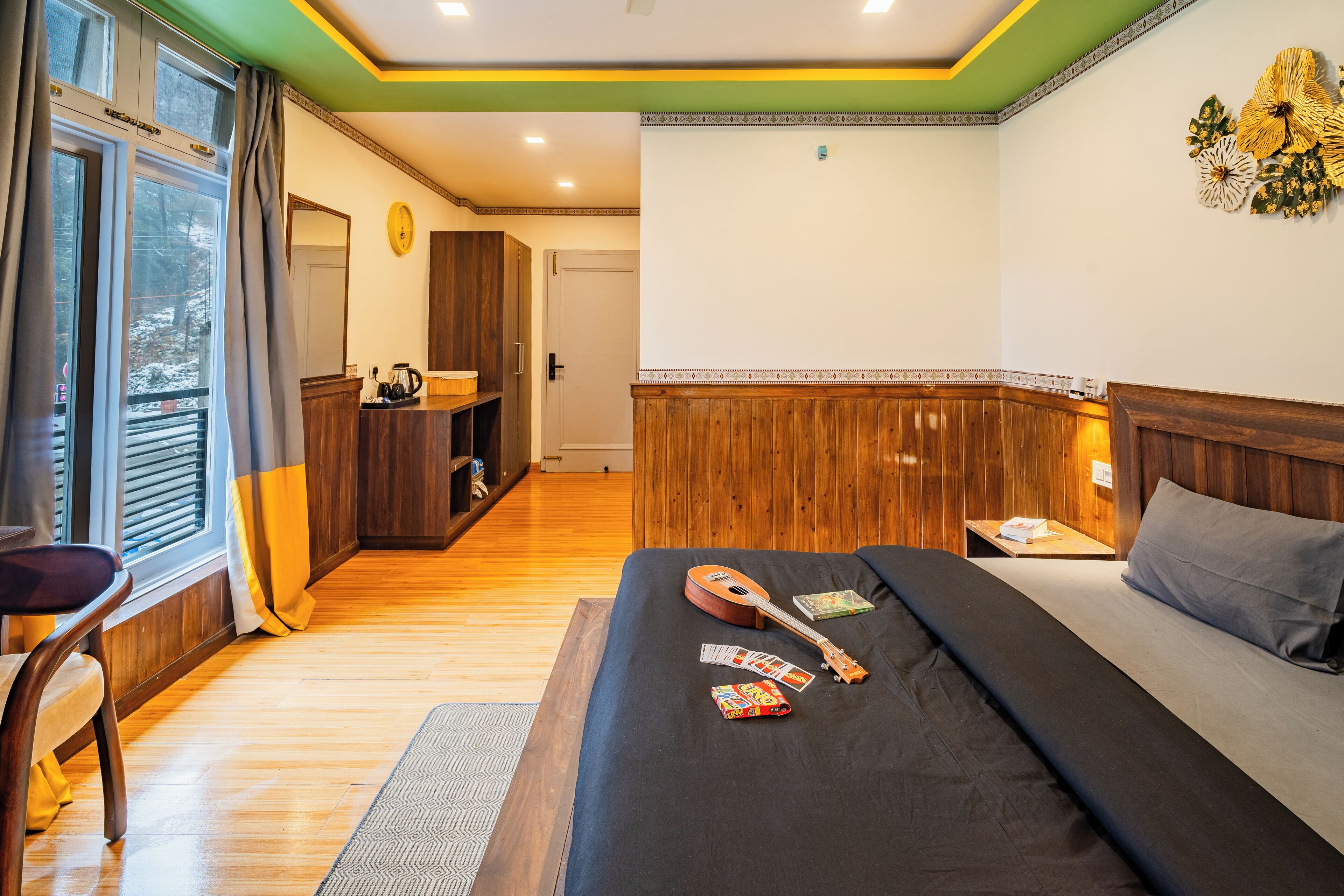 Una habitación de hotel con una cama, una guitarra y una cafetera sobre la mesita de noche.