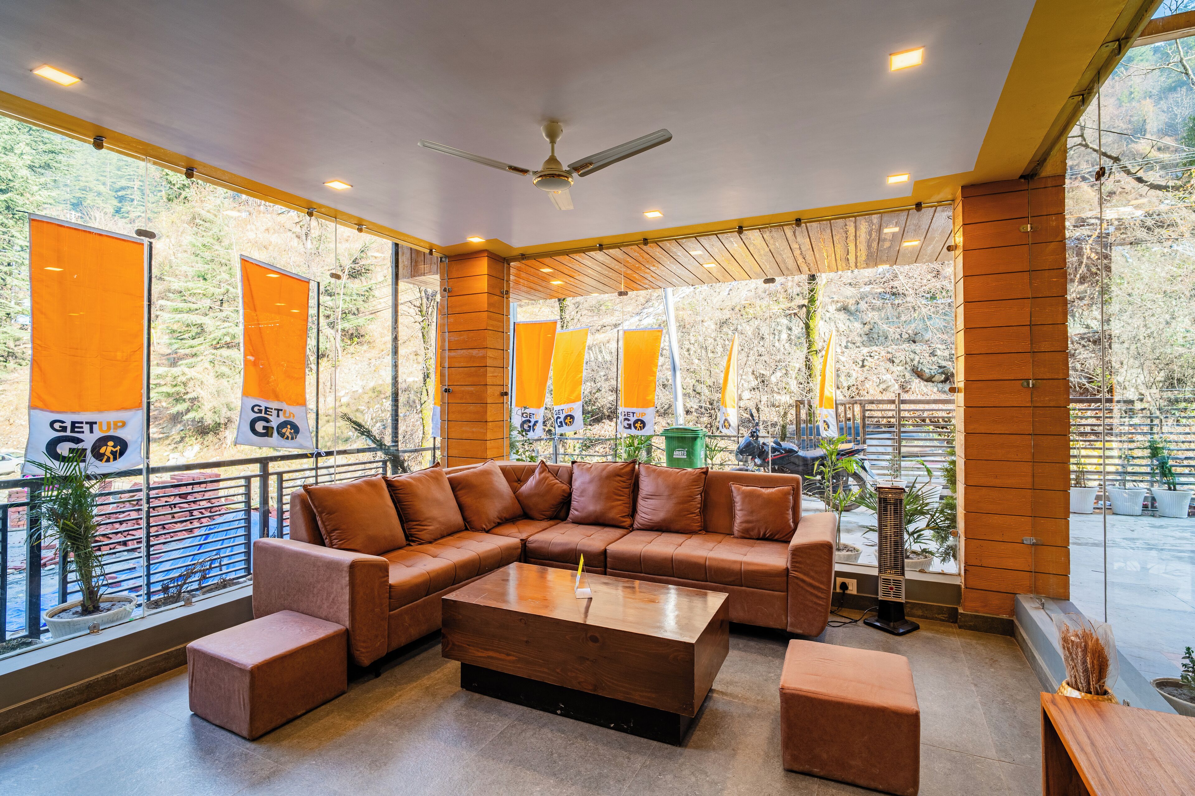 A modern lounge area with a sectional sofa, a coffee table, and large windows offering views of a forested area.