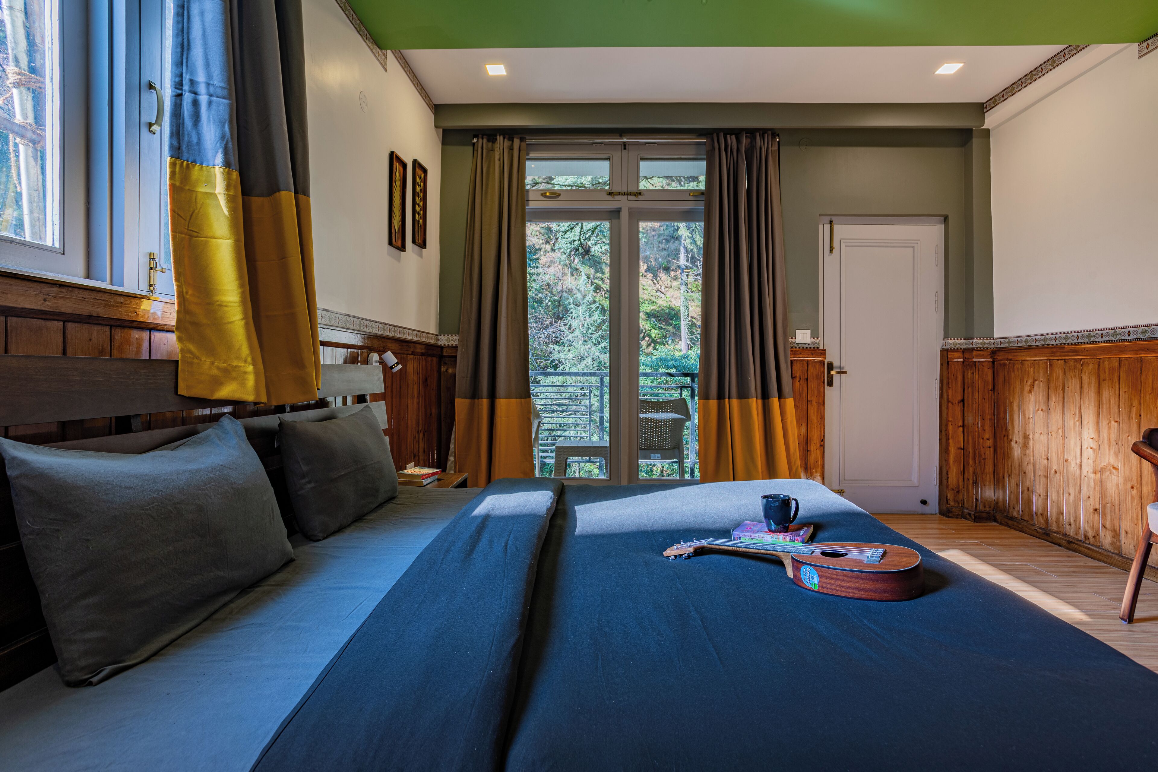 Une chambre d’hôtel avec un grand lit, une guitare et une vue sur l’extérieur grâce à une porte vitrée.