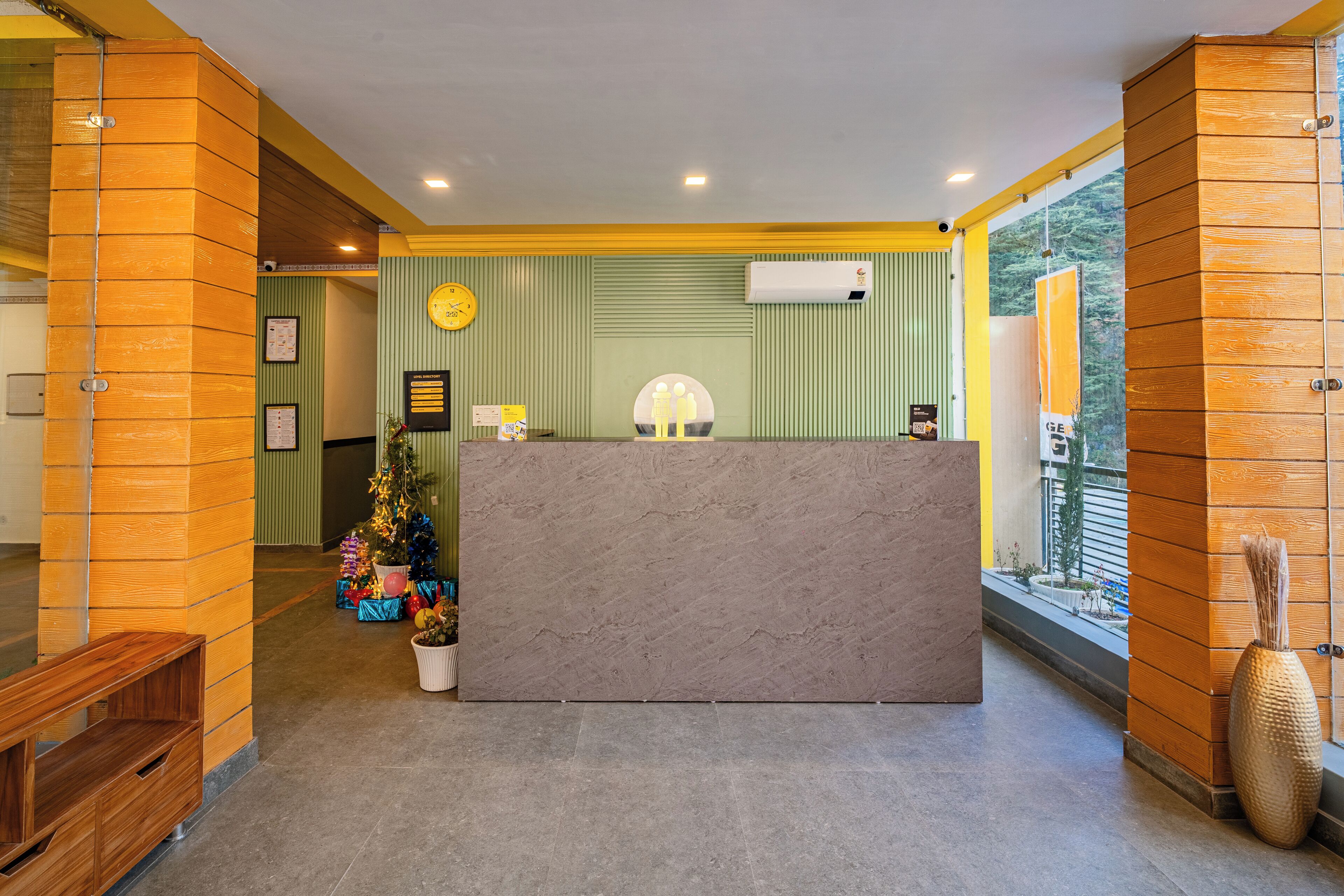 A reception area with a wooden reception desk, a Christmas tree, and a large window with a view of the outdoors.
