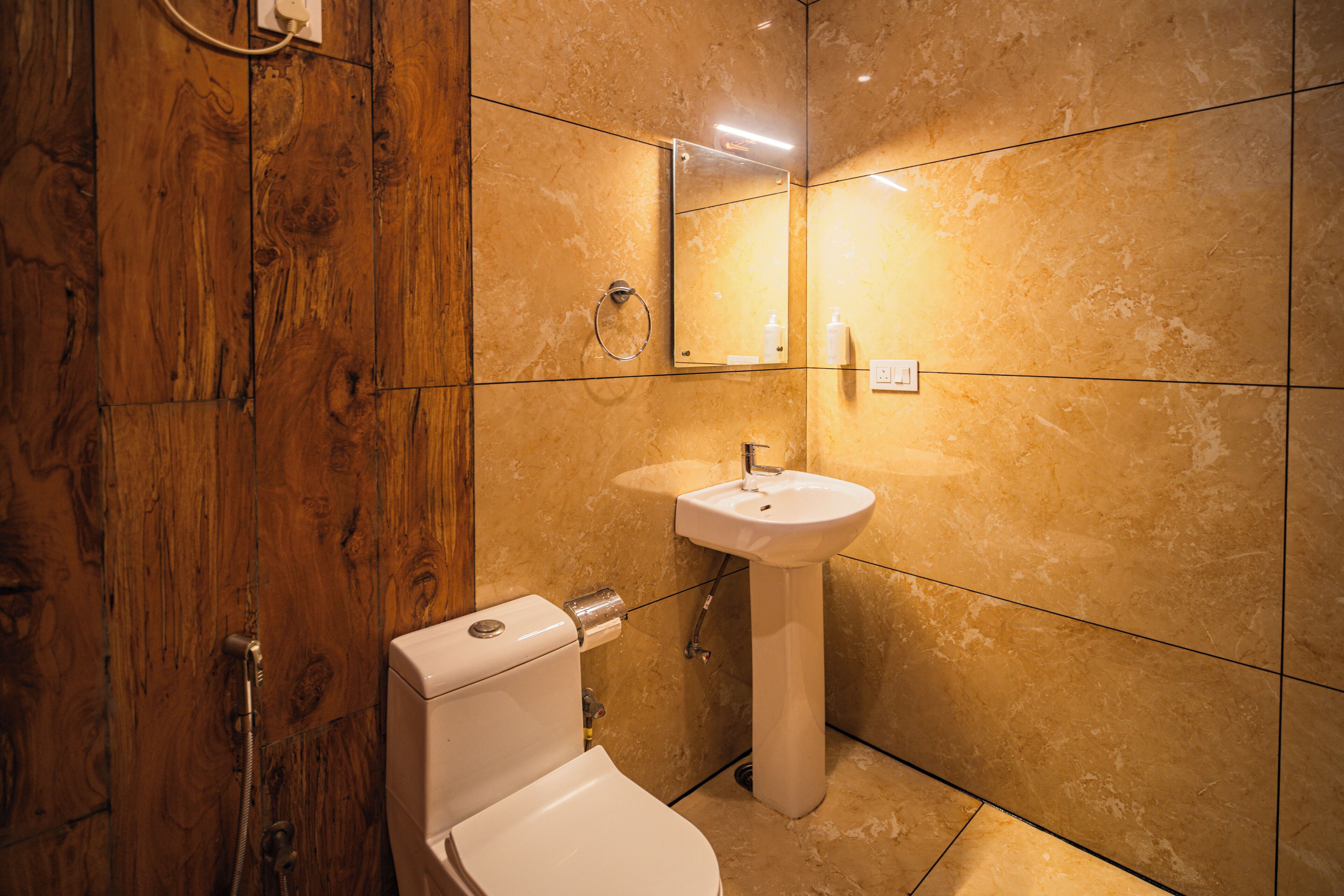 A bathroom with a wooden shower enclosure, a white toilet, and a sink with a mirror above it.
