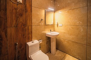 Un baño con cabina de ducha de madera, inodoro blanco y lavabo con espejo superior.