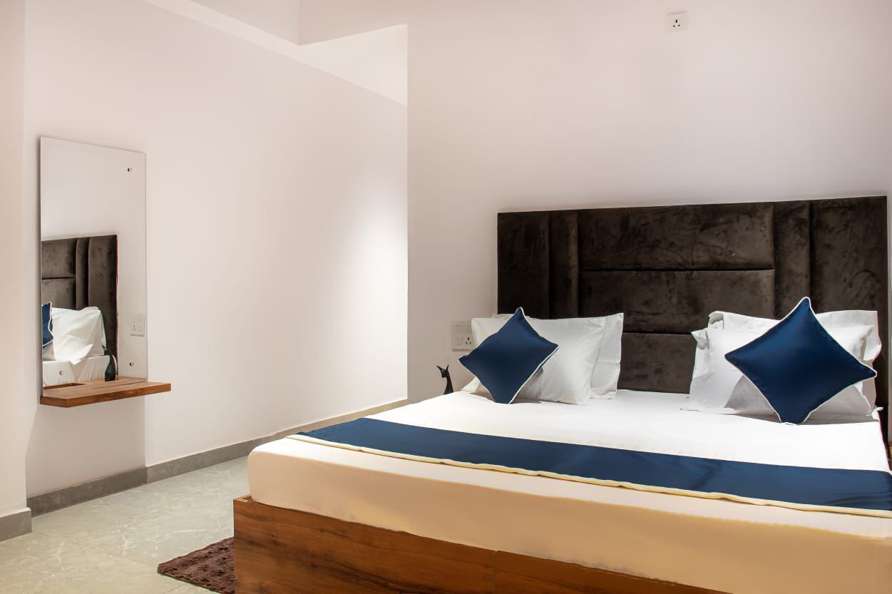 Un dormitorio moderno con una cama grande, cabecera de madera y un espejo en la pared.