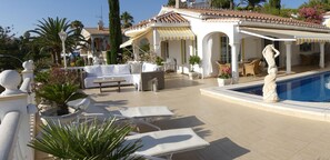 A poolside area with lounge chairs, a white sofa, and a statue. - Casa Jolanda: Stylish Villa with Sea View, Wi-Fi & Air Conditioning (Caleta de Vélez)