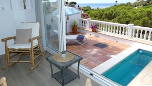 En balkon med pool, stol, bord og plantekasser.