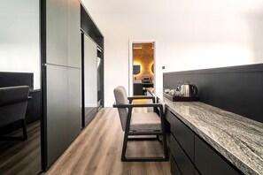 A modern kitchen with a granite countertop, a chair, and a television. - Tranquil Luxury Stay with Rice-Field & Ocean Views, Private Pool+Bar, Chef & BBQ (Bali)