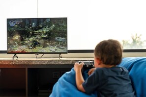A child playing a video game on a television. - Tranquil Luxury Stay with Rice-Field & Ocean Views, Private Pool+Bar, Chef & BBQ (Bali)