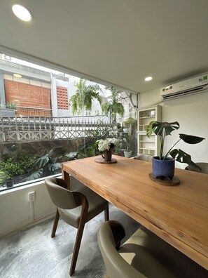 A modern dining area with a wooden table, chairs, and potted plants. - The Dates Villa (Ho Chi Minh City)