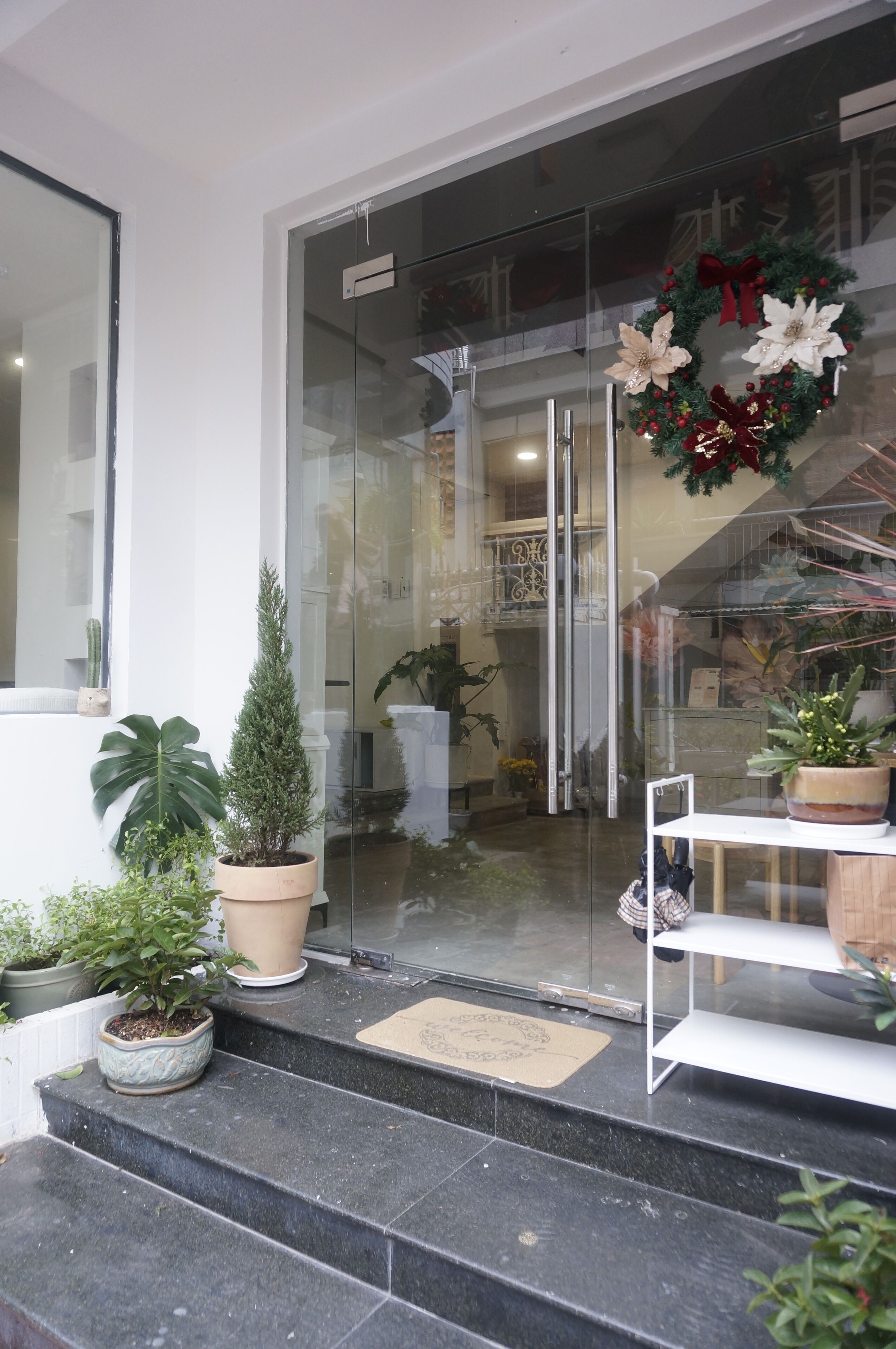 L’entrée d’un hôtel, avec une porte en verre, des plantes en pot et une couronne de Noël.