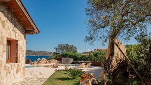 A stone building with a pool, outdoor seating, and a view of the sea. - Villa Tramas de Luna - Sardinia Unlimited (Capo Coda Cavallo)
