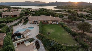 A luxurious villa with a swimming pool, outdoor seating, and a view of the surrounding landscape and water. - Villa Tramas de Luna - Sardinia Unlimited (Capo Coda Cavallo)