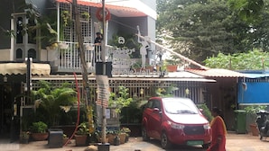 A building with a balcony, potted plants, and a red car parked in front. - Cozy room The Hole In The Wall  (Bengaluru)