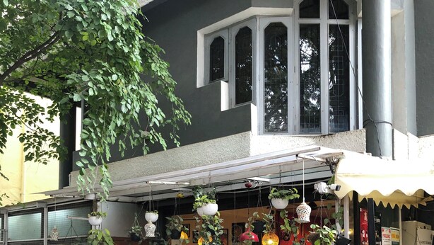 A cafe with hanging plants and a motorcycle parked in front. - Cozy room The Hole In The Wall  (Bengaluru)