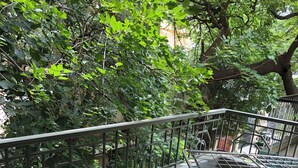 A balcony with a metal railing, a metal chair, and a tiled floor. - Cozy room The Hole In The Wall  (Bengaluru)