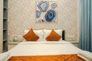 A hotel room with a bed, two pillows, a nightstand, a wall art piece, and a window with curtains. - White Mist by NAVA (Devanahalli)