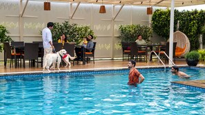 A swimming pool area with a lounge, seating, and a covered patio. - White Mist by NAVA (Devanahalli)
