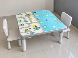 Una mesa con diseño de rompecabezas de paisaje urbano, dos sillas blancas y un piso de baldosas.