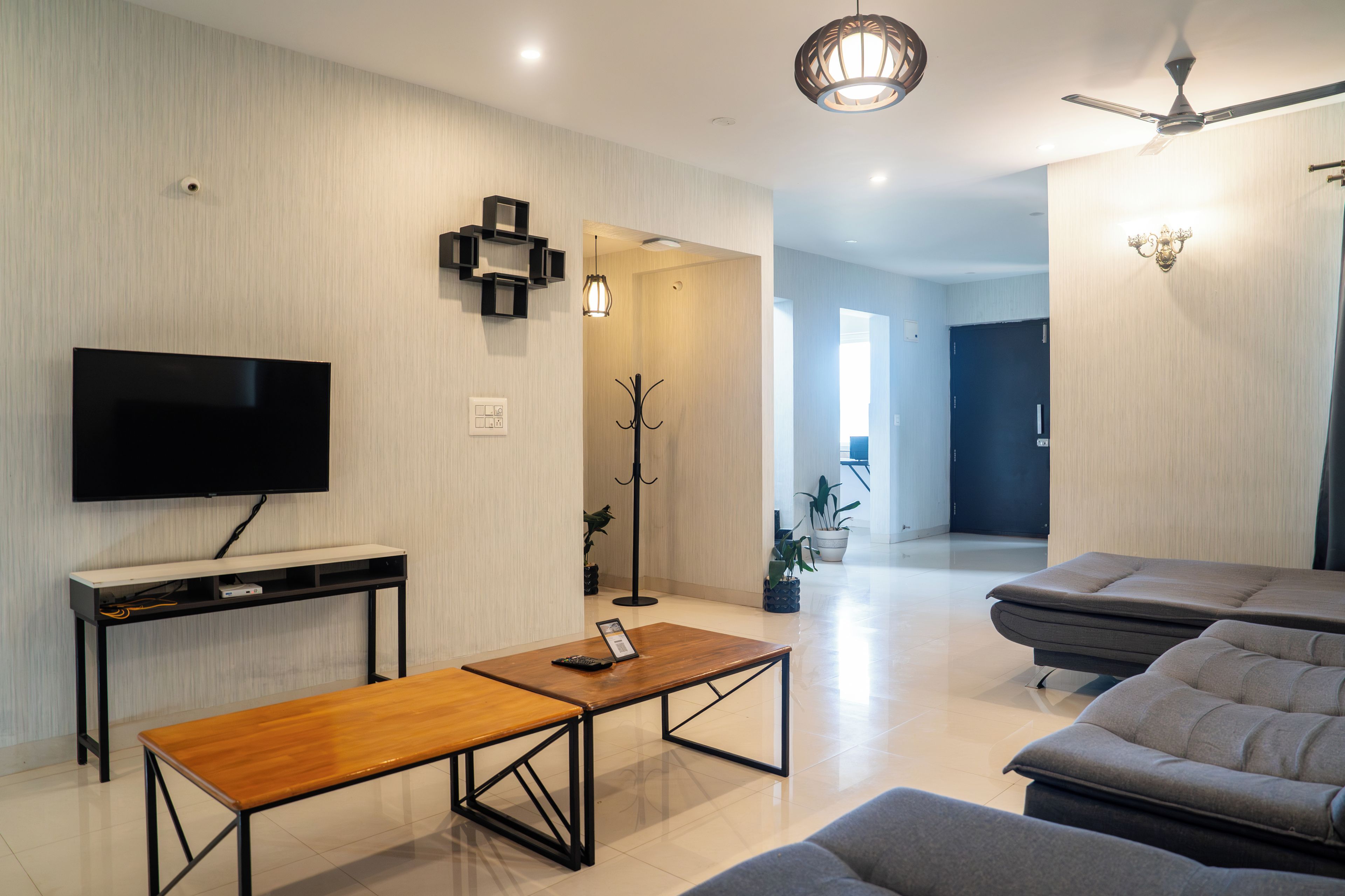 Ein modernes Wohnzimmer mit einem Flachbildfernseher, einem Holztisch, einer Couch und einem Deckenventilator.