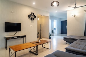 Una sala de estar moderna con una televisión de pantalla plana, una mesa de centro de madera, un sofá y un ventilador de techo.