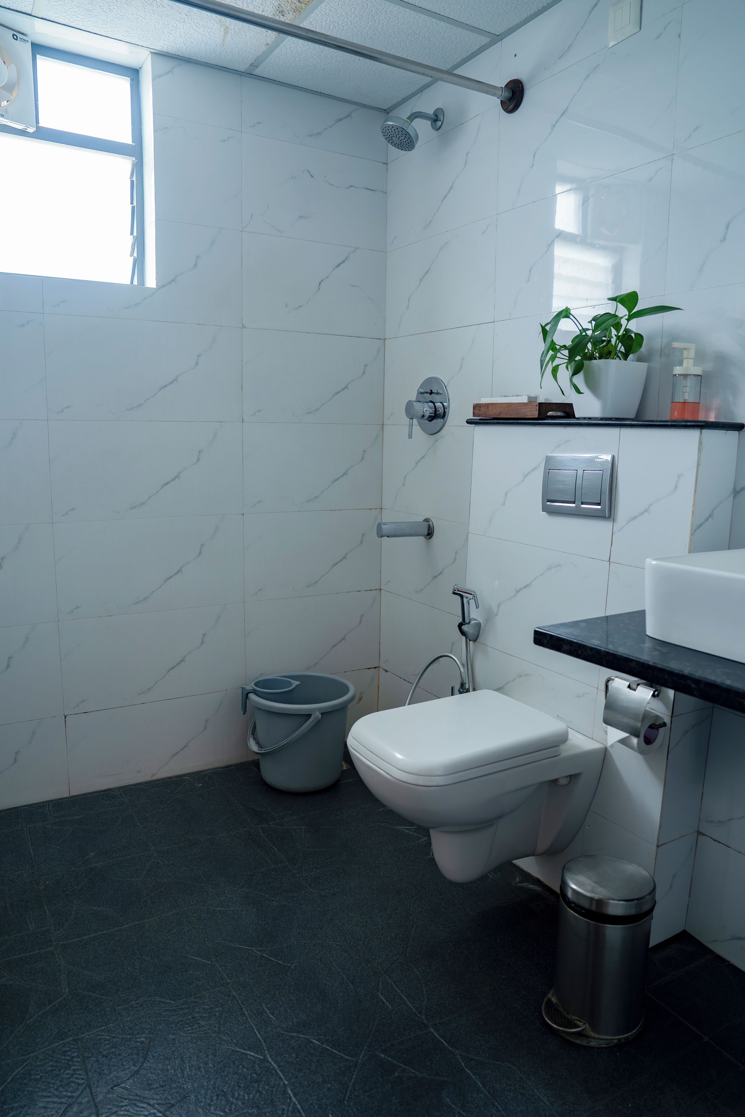 Un baño con inodoro, bidé, ducha y un pequeño cubo de basura.