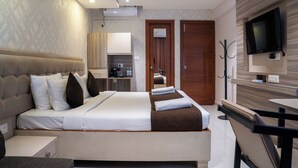Habitación de hotel moderna con una cama grande, televisor, escritorio y vistas a la cocina y al baño.